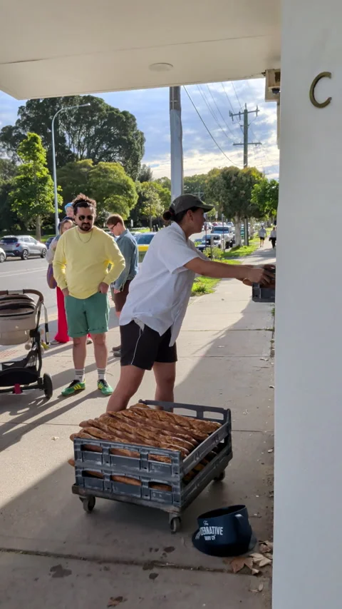 Baker delivers fresh bread rolls from a rolling cart to a shop entrance Stock Footage 340273630