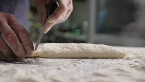 Baker dividing dough with bench scraper on floured surface. Stock Footage 284383474
