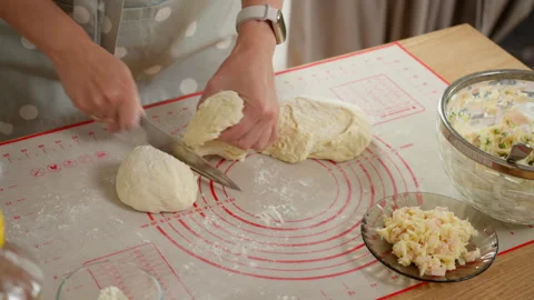 A baker dividing fresh dough into equal portions with a knife on a worktop Stock Footage 315906208