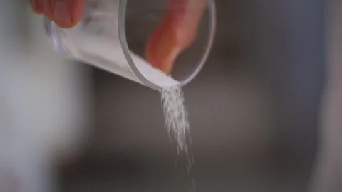 Baker dosing salt and preparing dough Stock Footage 76558480