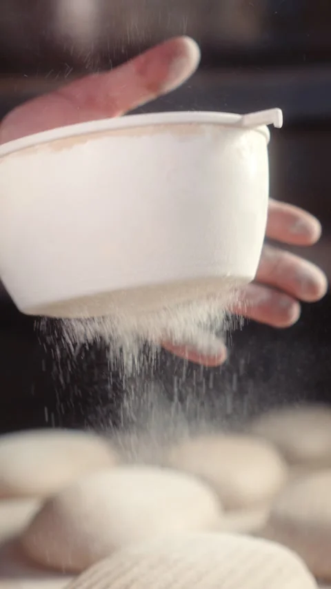 Baker dusting bread with flour using a flour shaker Stock Footage 344312958
