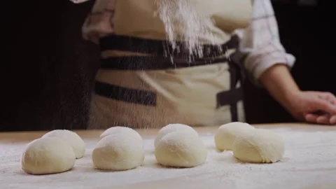 Baker dusting raw dough balls with flour on a wooden table preparing for ba.. Stock Footage 335059663