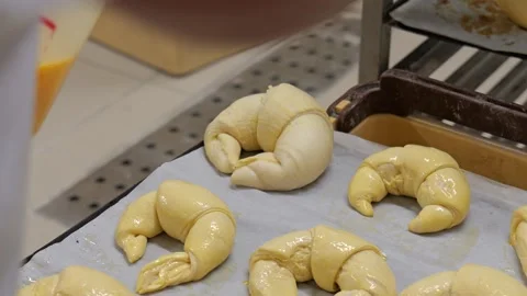 Baker Egg-Washing Freshly Shaped Croissants on Baking Sheet Video stock 336416171