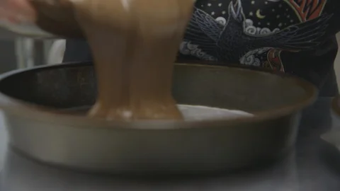 Baker filling tin with batter mixture for dessert Vidéo 104866592