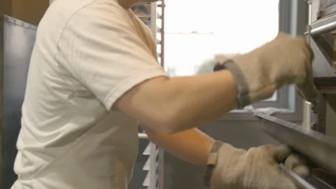 Baker flipping bread loaf trays back in the industrial oven Stock Footage 87612315