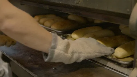Baker flipping bread loaf trays back in the industrial oven Stock Footage 87612331