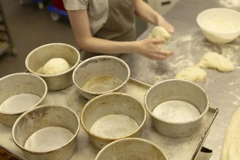 Baker forming dough in concentrated bakery kitchen overhead view with flour. Stock Photos