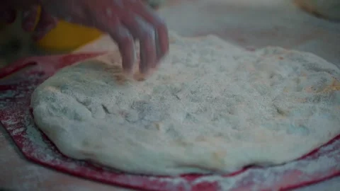 Baker forms flat dough with his hands and stands flour over it Stock Footage 242163296