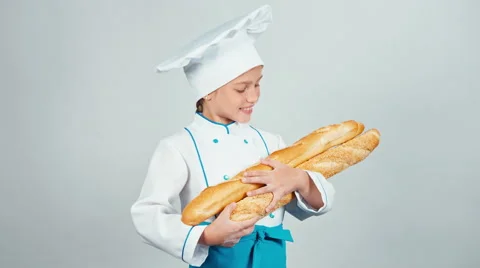 Baker girl 7-8 years child holds bread baguettes and smiling at camera isolated Stock Footage