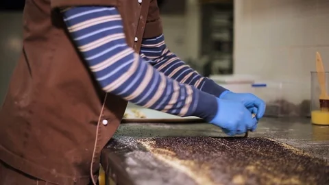 Baker in gloves and brown uniform at work Stock Footage 106484642
