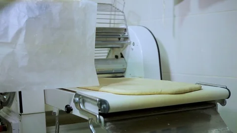 Baker with gloves puts the dough on Dough sheeter Stock Footage 106463397