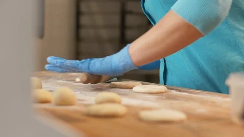 Baker hand rolling dough before baking pastries on table in bakehouse close up Stock Footage 90680599