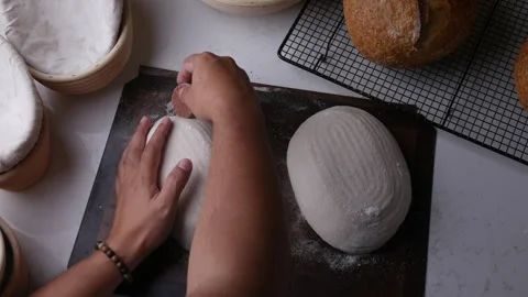 Baker hand scoring dough with a razor blade. Stock Footage 305981253