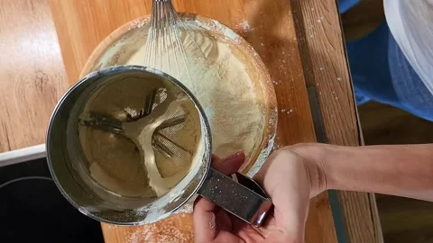 Baker hand stirring yellow mass with flour ingredient in stainless steel bowl Stock Footage 337257295