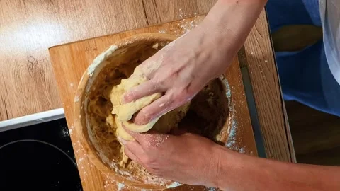 Baker hand stirring yellow mass with flour ingredient in stainless steel bowl Stock Footage 337358628