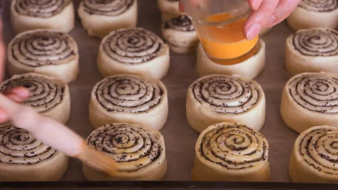 Baker hands with a brush covers the pastry with egg mixture. Closeup. Video stock 101140621