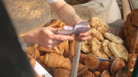 Baker hands cash and change to customer. Armenian money in baker hands. Selling  Stock Footage 332876410