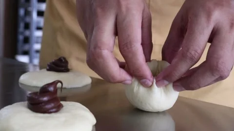 Baker hands folding chocolate bun dough Stock Footage 295787891