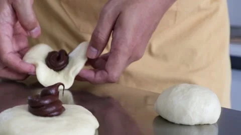 Baker hands folding chocolate bun dough Stock Footage 295787898