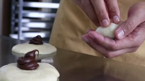Baker hands folding chocolate bun dough Stock Footage 295787916