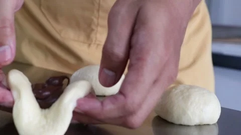 Baker hands folding chocolate bun dough Stock Footage 295787920