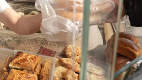 Baker hands fresh flatbreads in bag to customer at street bakery window. Baking  Stock Footage 332876380