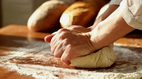 Baker hands kneading dough in flour on table, slow motion Stock Footage