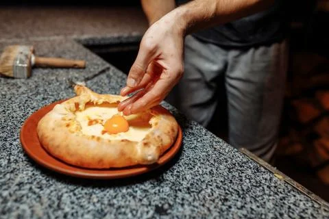 Baker hands preparing khachapuri on kitchen table. cook making traditional ge Stock Photos
