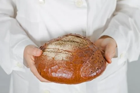 Baker holding fresh bread in the hands of Stock Photos