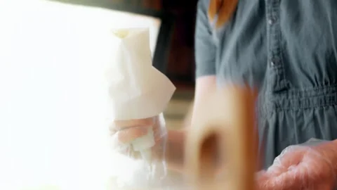 Baker holding a piping bag at a bright kitchen workstation, 4K Stock Footage 341119628
