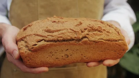 The baker holds in hands a of fresh bread close-up. Artisan bread is making by Stock Footage 268033052