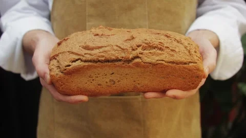 The baker holds in hands a of fresh bread close-up. Artisan bread is making by Stock Footage 270187447