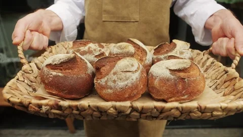 The baker holds in hands a of fresh bread close-up. Artisan bread is making by Stock Footage 270484124