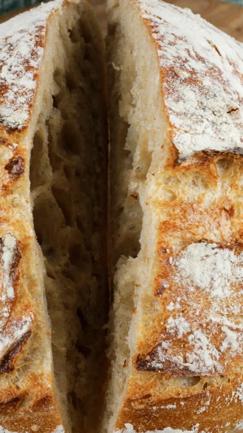 A baker holds two halves of freshly baked homemade wheat sourdough bread. Stock Footage 341500183