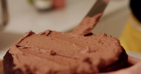 Baker icing the top of a chocolate cake with chocolate frosting Stock Footage 247785750