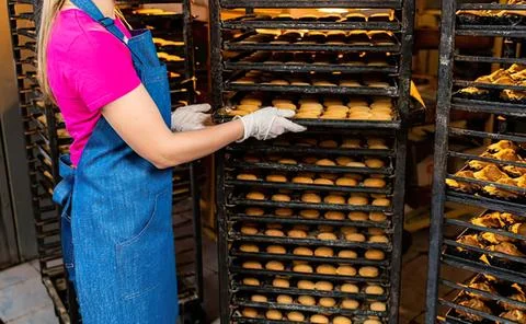 Baker inspecting baked bread in a bakery oven Stock Photos