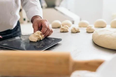 Baker kneading dough in a bakery. Stock Photos