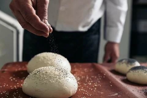 Baker kneading dough in a bakery. Stock Photos