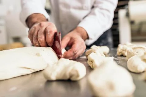Baker kneading dough in a bakery. Stock Photos
