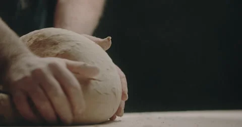 Baker kneading dough on counter black background Stock Footage 254960069