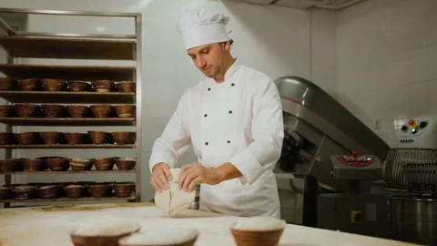 Baker kneading dough in flour on table fot the future loafs of bread in the Stock Footage 78261331