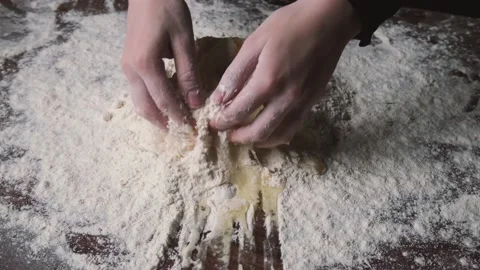 Baker kneading dough in flour on table. Process of mixing flour with egg and Stock-Footage 131237992