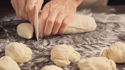 Baker kneading dough in flour on table and cutting into pieces. 스톡 동영상 261451982