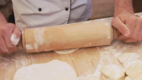 Baker kneading dough with rolling pin on table. Close up on the hands making Stockbeeldmateriaal 83087287
