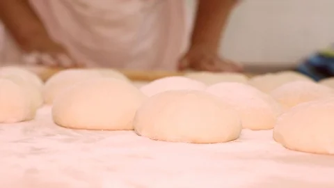 Baker kneading dough with rolling pin on table. Woman rolling dough for pizza. R Stock Footage 90732586
