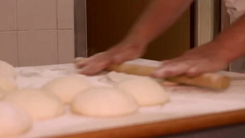 Baker kneading dough with rolling pin on table. Woman rolling dough for pizza. R Stock Footage 90733009