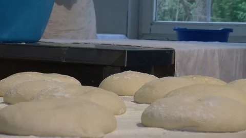 Baker kneading dough with rolling pin on table. Woman rolling dough for pizza. 動画素材 90733368