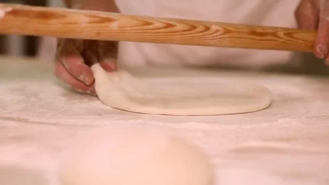 Baker kneading dough with rolling pin on table. Woman rolling dough for pizza. R Stock Footage 90735579