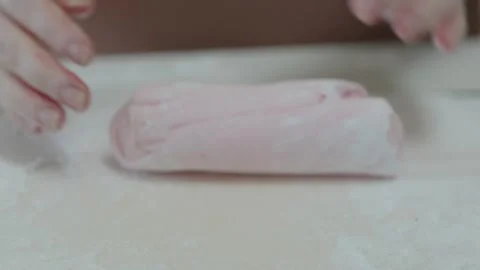 A baker kneads and rolls pink coloured fondant icing by hand. Stock Footage 319830589