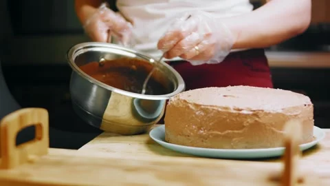 Baker ladling chocolate glaze over a buttercream cake, 4K Stock Footage 341121081